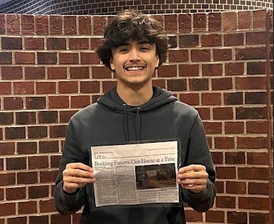 Hunter Mallory holding up a laminated copy of "Building Futures One House at a Time," the first article he wrote for "The Pitchfork Press." This article was later picked up by the "South Lake County Sun," the new local newspaper for Cedar Lake and Lowell.