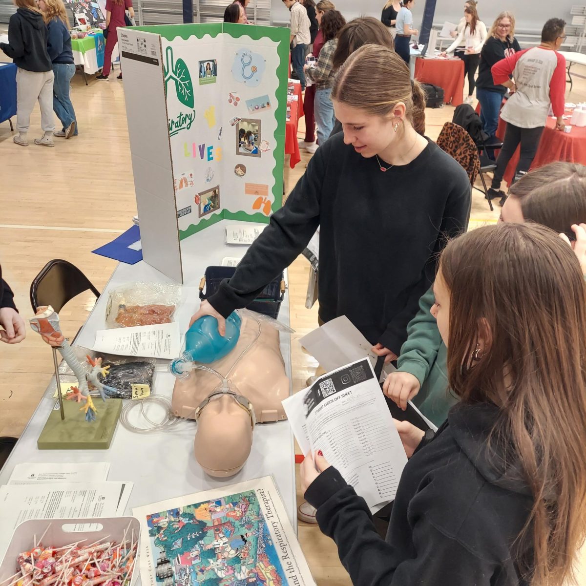 Molly Berg actively uses a resuscitation bag on a medical mannequin.