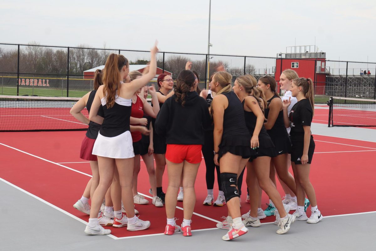 The girls tennis team has a huddle before their first match of the season.